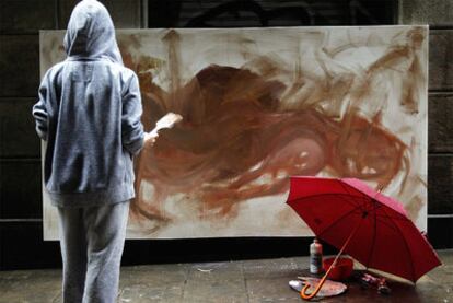 Una artista frente a su lienzo en la lluviosa mañana de ayer en la calle de Ataülf de Barcelona.