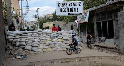 Unos niños pasan junto a una de las barricadas levantadas en la localidad de Cizre por jóvenes kurdos simpatizantes del PKK.