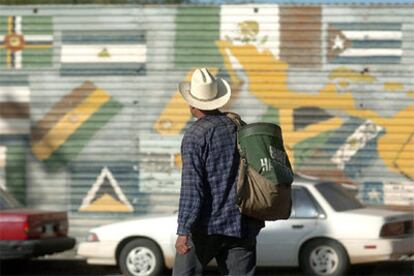 Un emigrante camina frente al muro que divide la frontera de EE UU y México.