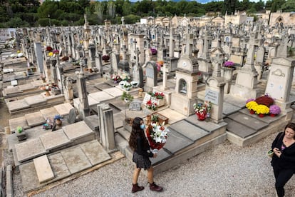 Varias personas llevan flores a las tumbas de sus seres queridos en el cementerio de Palma de Mallorca con motivo de la celebración del Día de todos los Santos.