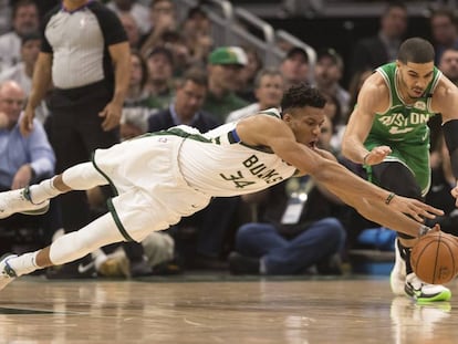 Antetokounmpo y Tatum se lanzan a por un balón.