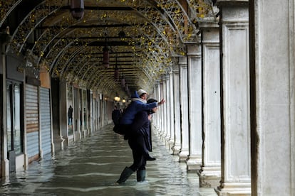 Una mujer recibe la ayuda de otra persona para cruzar la plaza de San Marcos en Venecia, este sábado. El objetivo de las barreras móviles es proteger la histórica ciudad y sus edificios del agua del mar y del efecto corrosivo de la sal, que amenaza a un patrimonio de alto valor artístico y arquitectónico.