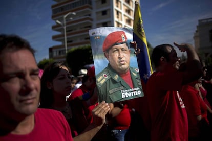 Una mujer sujeta un poster con la imagen de Hugo Chávez, en el primer aniversario de su muerte, en la Habana (Cuba).