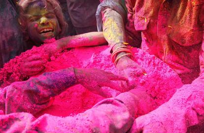 Varios indios cogen polvo de colores durante la celebración del Holi en Uttar Pradesh (India), el 27 de febrero de 2018.