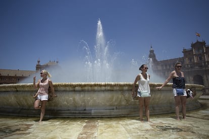 Tres chicas se refrescan en la fuente de la Plaza de España, en Sevilla.