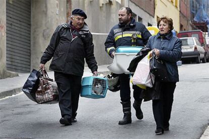 Afectados por el hundimiento del Carmel salen de recoger enseres de sus domicilios acompañados por un bombero.