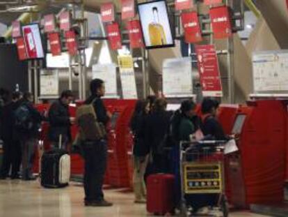 Varias personas guardan cola junto a los mostradores de facturación de la Terminal T4 del aeropuerto de Madrid-Barajas. EFE/Archivo