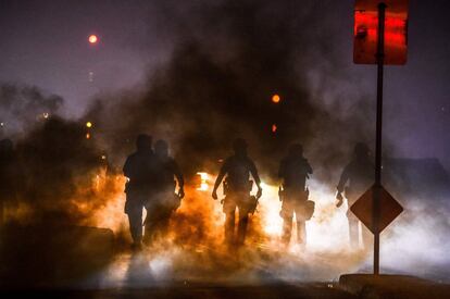 Na rua Lake, onde ocorreram alguns dos episódios mais violentos durante a madrugada deste domingo, vários edifícios foram incendiados. Na imagem, policiais lançam gás lacrimogêneo para dispersar os manifestantes em Mineápolis.