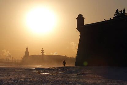 Varias personas caminan por la Fortaleza de Pedro y Pablo durante una puesta de sol, cerca del río Nevá, en San Petersburgo, Rusia.