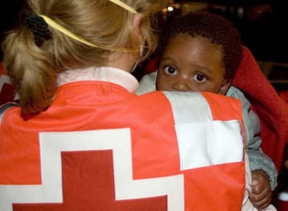 Una sanitaria traslada al único menor superviviente de los 10 que embarcaron en la patera.