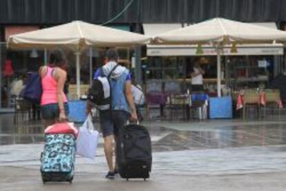 Unos turistas caminan con sus maletas por el barrio de La Barceloneta. 