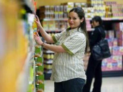 Una empleada embarazada de la cadena de supermercados Mercadona coloca art&iacute;culos en una estanter&iacute;a. 