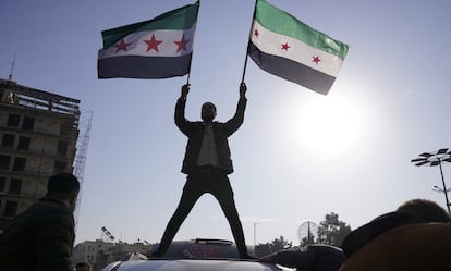 Un hombre con dos banderas de la oposición siria celebra el derrocamiento de Bachar el Asad este domingo en Alepo.