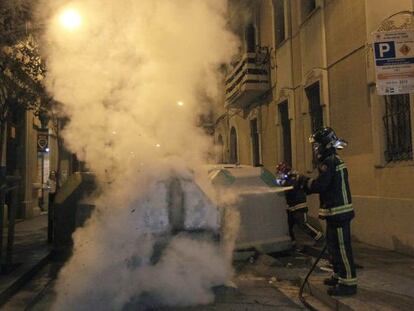 Los bomberos apagan un contenedor encendido en la manifestaci&oacute;n del jueves pasado en Gr&agrave;cia.