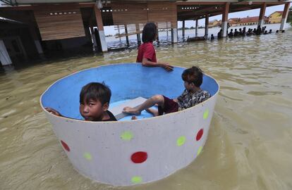 Una madre traslada a sus hijos en una bañera, por una calle inundada de Bekasi (Indonesia).