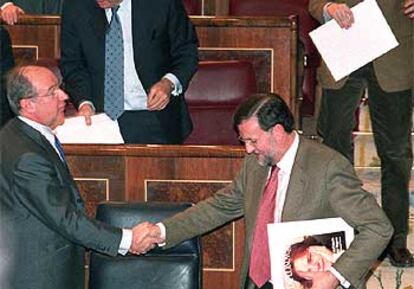 El vicepresidente primero, Rodrigo Rato, saluda al secretario general del PP, Mariano Rajoy, al final del pleno.