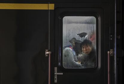 Un hombre mira por la ventana de un tren en la estación de Pekín.