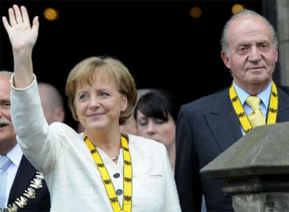 Angela Merkel saluda tras recibir el premio acompañada por el rey Juan Carlos ayer en Aquisgrán.