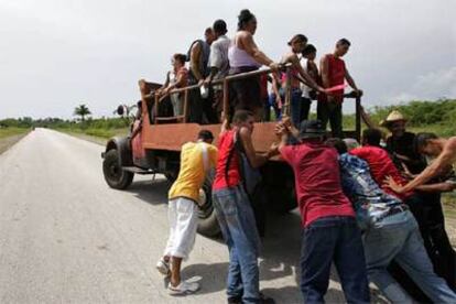 En la imagen, un grupo de cubanos empuja un camión para trasladarse.
