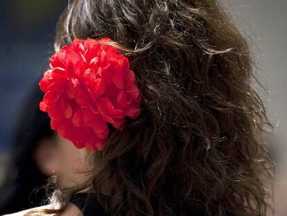 Una mujer luce una flor en el pelo mientras pasea por la calle Larios.