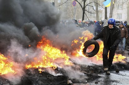 Un manifestante sostiene un neumático en llamas durante los enfrentamientos entre opositores y policía despues de varias semanas de tregua, en Kiev.