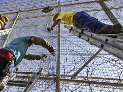 Operarios instalan alambres con cuchillas en la valla de Melilla.