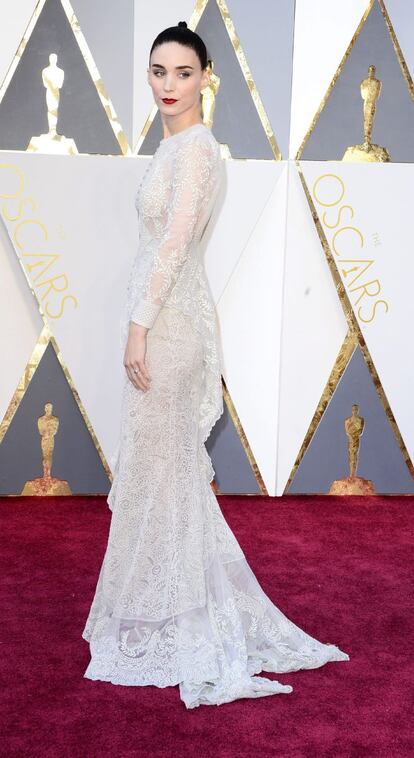 Rooney Mara, de 30 años, eligió a la firma Givenchy para su ‘look’ en la alfombra roja de los Oscar. La nominada a mejor actriz de reparto por su interpretación en ‘Carol’ suele apostar por diseños en colores discretos. Esta vez se decantó por un blanco perlado. El vestido, de mangas largas y una pequeña abertura a la altura de la cintura, concentra su protagonismo en la espalda abierta. Su estilo es una vez más sobrio. Entre sus diseñadores favoritos destacan Valentino, Alexander McQueen, Balenciaga y Givenchy.

Su estilo enigmático siempre la ha diferenciado en las alfombras rojas. Sin embargo, la protagonista de ‘Los hombres que no amaban a las mujeres’ asegura que nunca ha sido su intención ser distinta. “La verdad es que no es mi intención ser la rara. Al revés, tengo la sensación de vestir siempre lo mismo”, dijo en 2013. La actriz también ha confesado que no presta mucha atención a su estilo, pero que cuenta con un estilista que la aconseja, aunque no siempre le haga caso. “Recuerdo que para Millennium quise vestir de negro y tuve que escuchar el discurso de que uno no viste de ese color en la alfombra roja porque nadie te hace caso. Pero me dio igual. Fui de negro. No quiero decir que me empeñe en llevar la contraria. Lo que deseo es ir cómoda y a mi gusto”, dijo.