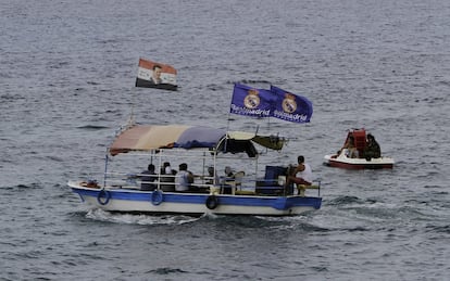 Duas bandeiras do Real Madrid e uma bandeira da Síria com uma imagem do presidente Bashar al-Assad em um barco que navega na costa de Latakia, Síria.