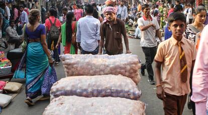 Un hombre transporta varios sacos de cebollas en uno de los principales mercados de Bombay.