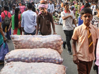Un hombre transporta varios sacos de cebollas en uno de los principales mercados de Bombay. 