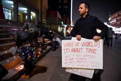 Un hombre sostiene una pancarta mientras varios niños encienden velas frente al Teatro Nacional de Kosovo, el 17 de diciembre de 2016.