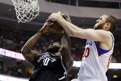 Spencer Hawes, de los Sixers, y Reggie Evans, de los Nets, pelean un rebote.