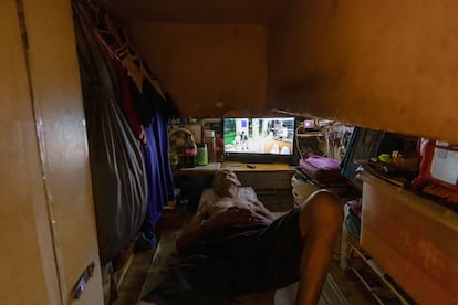 Sum, de 72 años, posa para la fotografía en su “casa ataúd” en Hong Kong, el 15 de agosto de 2024.  Este hombre, que durmió durante un año en un paso elevado en la calle, vive desde hace tres años en este espacio minúsculo, por el que paga 2.500 dólares hongkoneses (306 euros) de alquiler al mes. Un póster del Año Nuevo Chino en la puerta de su casa dice “Paz y seguridad vayas donde vayas”. En el interior, un televisor ocupa casi la mitad del espacio, que este hombre define como un refugio básico donde puede vivir en paz. Alrededor de 1,4 millones de los 7,5 millones de habitantes de Hong Kong viven en la pobreza, y el número de hogares pobres aumentó a 619.000 en el primer trimestre de 2024, lo que representa alrededor del 22,7 % del total, según la ONG Oxfam.