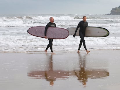 Dos surfistas, en la playa de San Lorenzo de Gijón, con la comunidad bajo aviso por bajas temperaturas.