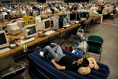 Un joven duerme en su colchoneta en uno de los pabellones de la Feria de Valencia que alberga la Campus Party.