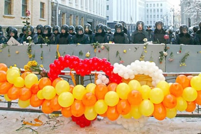 Policías antidisturbios, con escudos decorados con flores y detrás de una guirnalda de globos con los colores de la oposición, montan guardia delante de la sede de la Presidencia, ayer en Kiev.