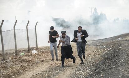 Hombres kurdos huyen de los enfrentamientos entre policía y manifestantes que apoyan a la ciudad de Kobanicerca de la frontera siria en Suruc, ciudad turca a la que han llegado miles de refugiados sirios.