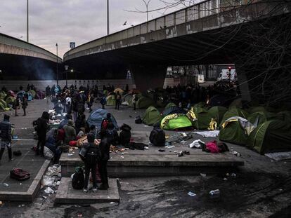 Migrants stand beside tents at dawn on January 29, 2019 at a makeshift camp set up under Paris' ring road in the north of Paris' area of Porte de la Chapelle, before its evacuation in an operation led by local authorities to shelter volunteer migrants in nearby gymnasiums and to examinate their insalubrity condition and administrative situation. (Photo by Christophe ARCHAMBAULT / AFP)