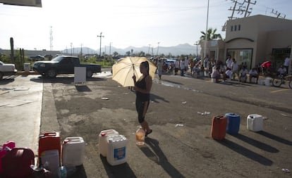 Una mujer espera su turno frente a una gasolinera de San José de los Cabos para rellenar de gasolina su botella.