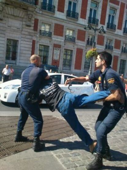 Uno de los detenidos es reducido por dos agentes.