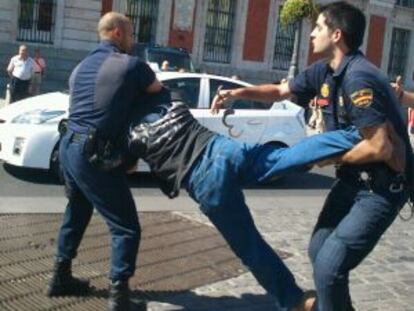 Uno de los detenidos es reducido por dos agentes.