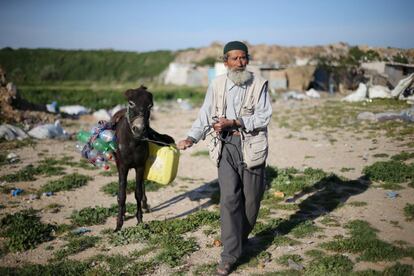 Un hombre palestino conduce a su burro, cargado con un bidón y botellas vacías, mientras va a llenarlos de agua potable en Jan Yunis (al sur de la Franja de Gaza).