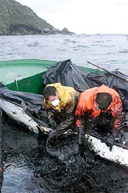 Dos voluntarios recogen pegotes de fuel a mano en las islas Cíes.