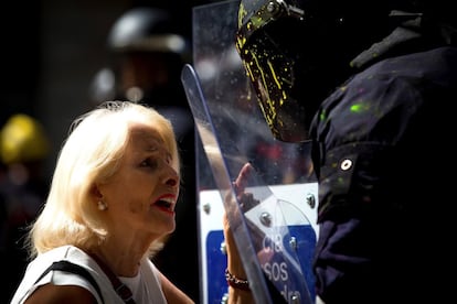 A woman speaks with a Mossos officer who has been covered with paint from the paint bombs thrown by CDR protesters.