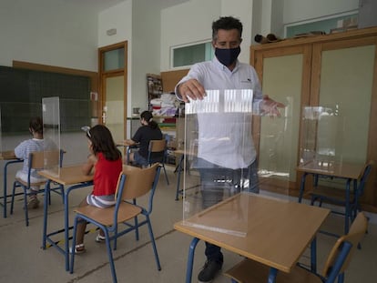 Varias niñas prueban las mamparas de seguridad instaladas en las mesas de un aula del colegio 'Carmen Borrego' en la localidad sevillana de El Rubio, financiadas con el dinero de las fiestas municipales.