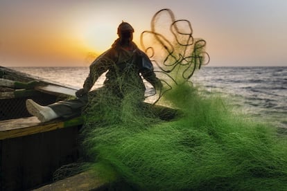 Un joven pescador echa la red al mar al caer la noche, a unos 65 kilómetros de la costa africana.