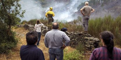 Un brigadista y varios vecinos miran un foco del incendio que asol&oacute; el t&eacute;rmino municipal de Navia de Suarna (Lugo).