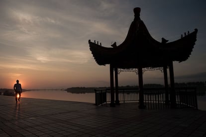 Um homem caminha próximo da Ponte da Amizade Sinocoreana, na margem chinesa do rio Yalu, que liga a cidade norte-coreana de Sinuiju a Dandong, na China.