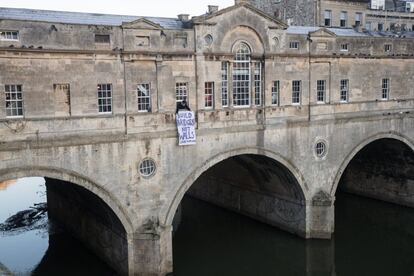 Una mujer coloca una pancarta en un balcón donde se lee el eslógan: "Construye puentes, no muros", en el puente Pulteney de Bath (Inglaterra).