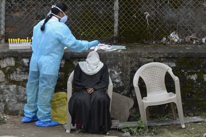 Una sanitaria recolecta una muestra de una mujer para detectar el coronavirus en un centro de salud de Hyderabad, La India.